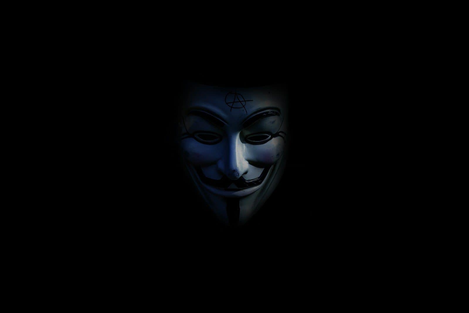 A Guy Fawkes mask with an anarchy symbol on a black background