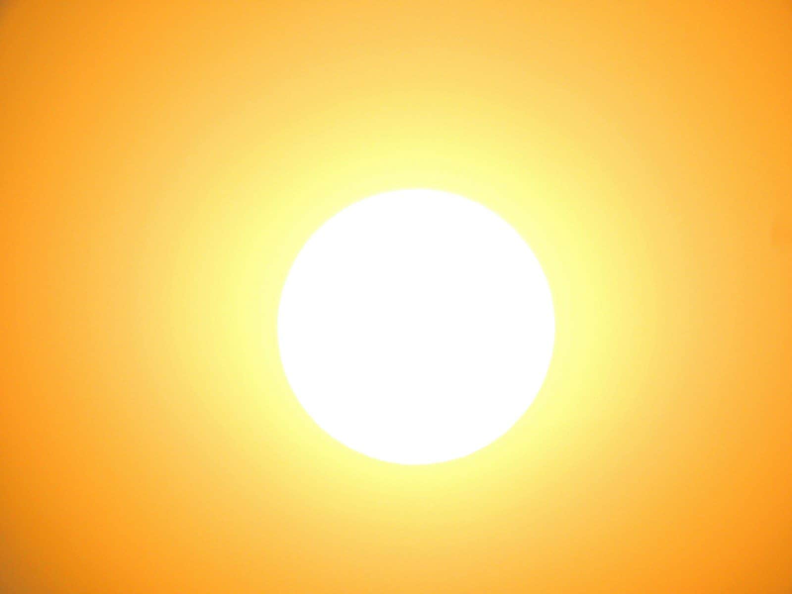 A bright white sun centered against a vibrant orange sky