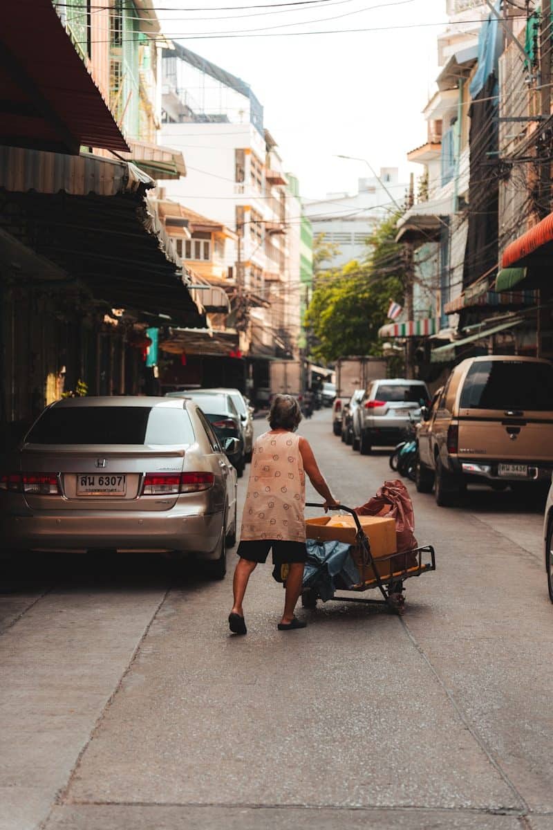 An elderly person pushes a cart down a narrow street