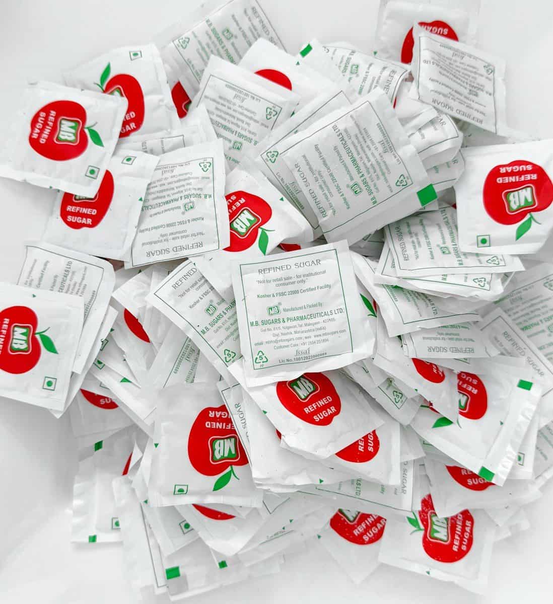 Numerous small white sachets with red apple branding