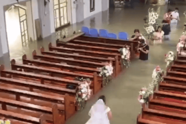 Casal mantém casamento mesmo com igreja alagada e noiva caminha pela água até o altar