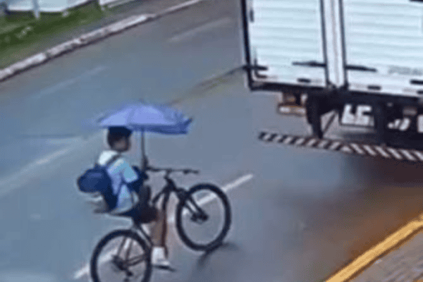 Ciclista não vê caminhão por causa de guarda-chuva e sofre queda durante chuva