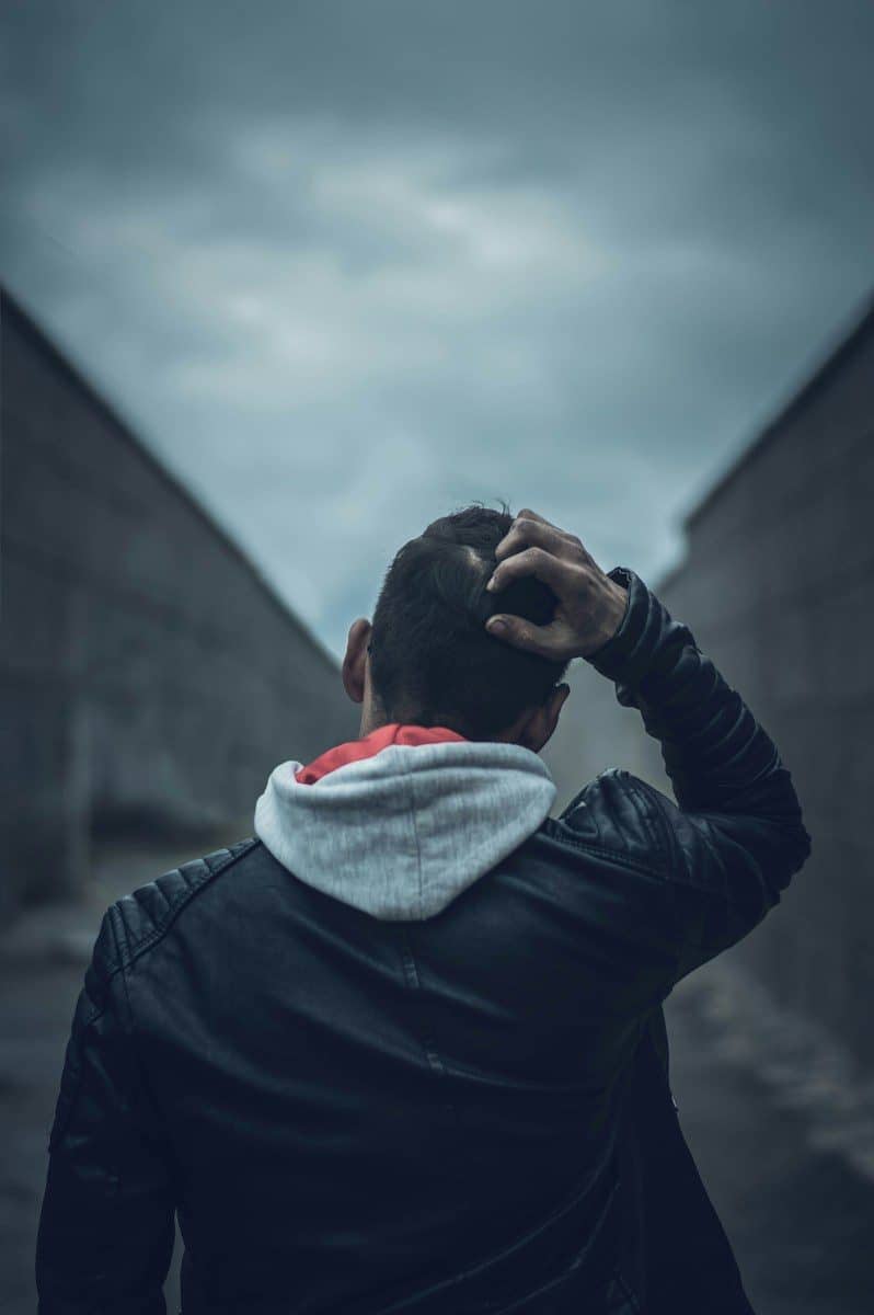 man in black leather jacket covering his face with white and red scarf