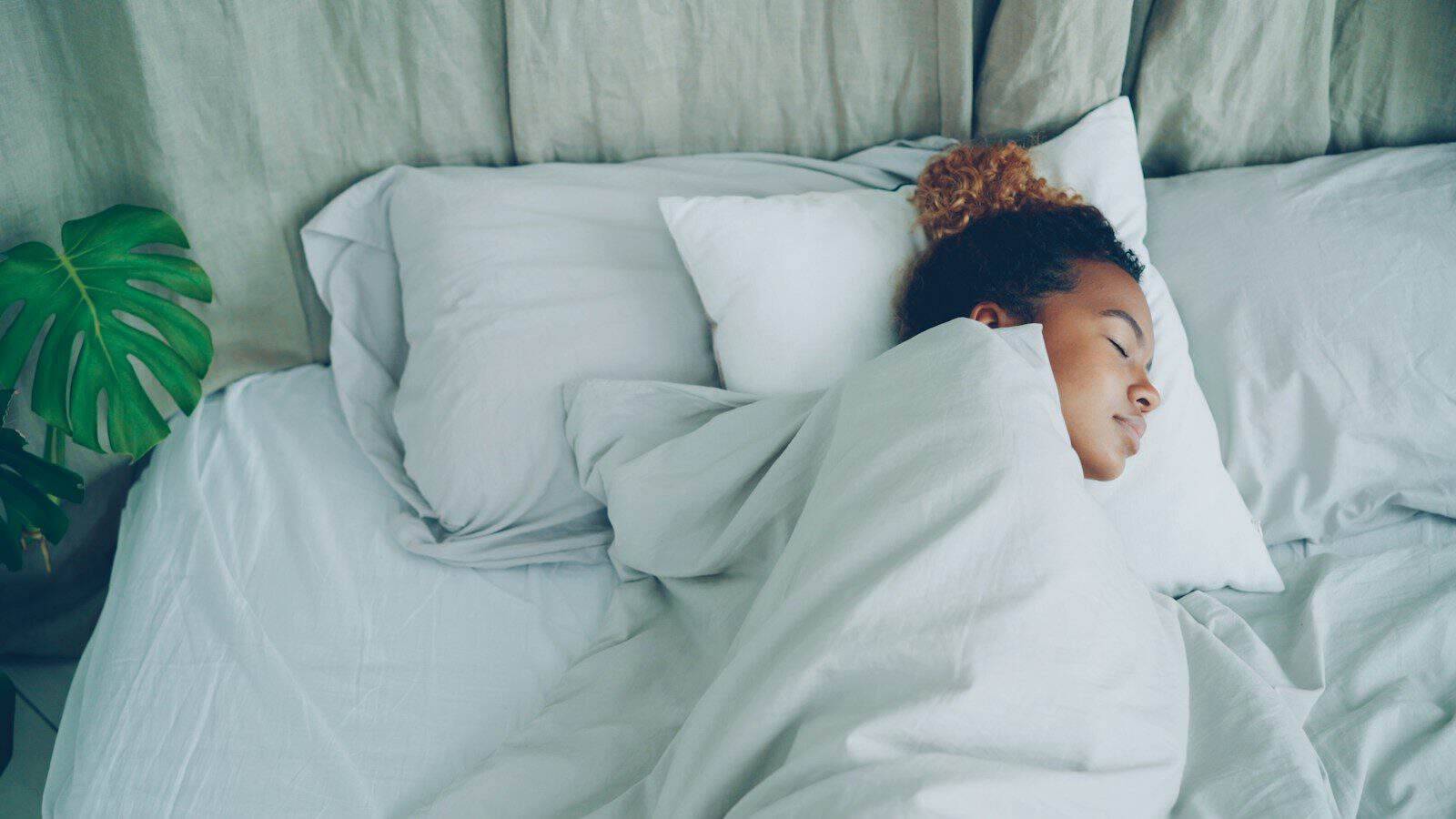 A young woman sleeping peacefully in a white bed