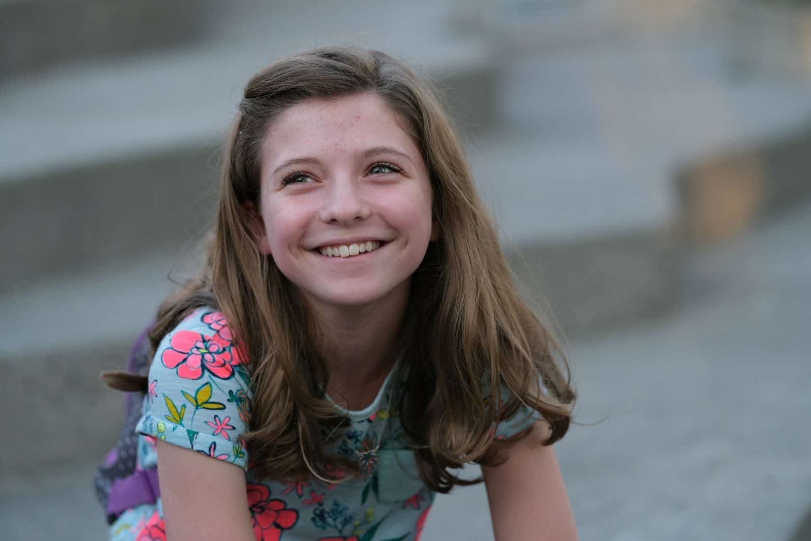 A young girl sitting on steps smiling for the camera