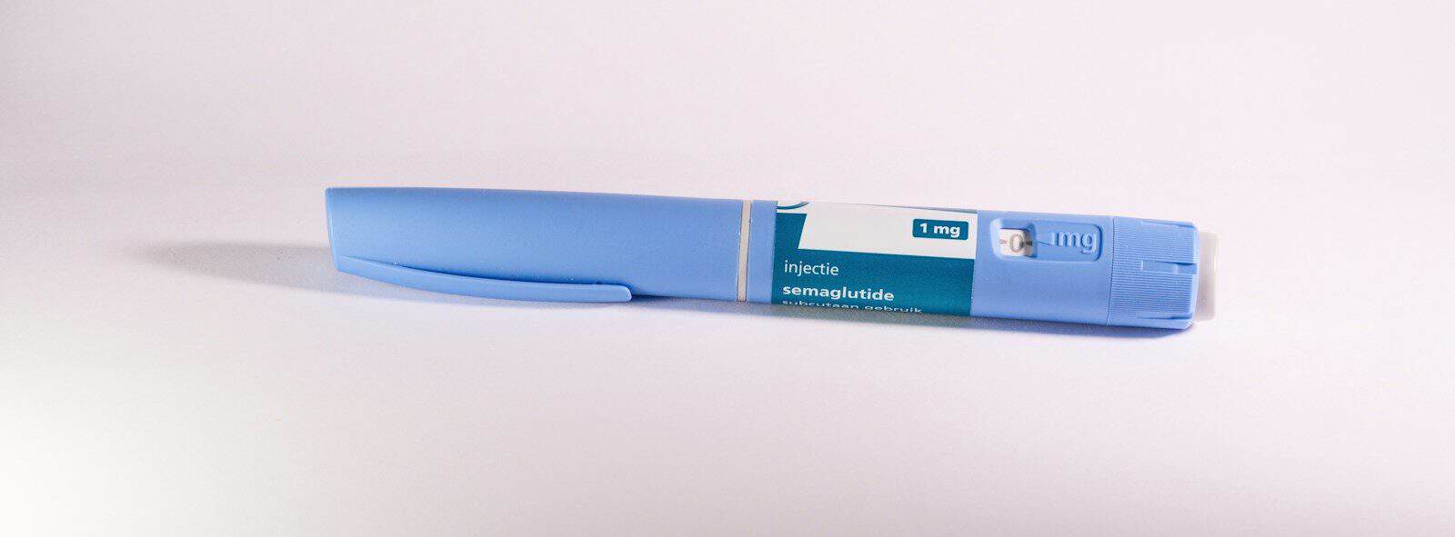 A blue insulin pen rests on a white surface
