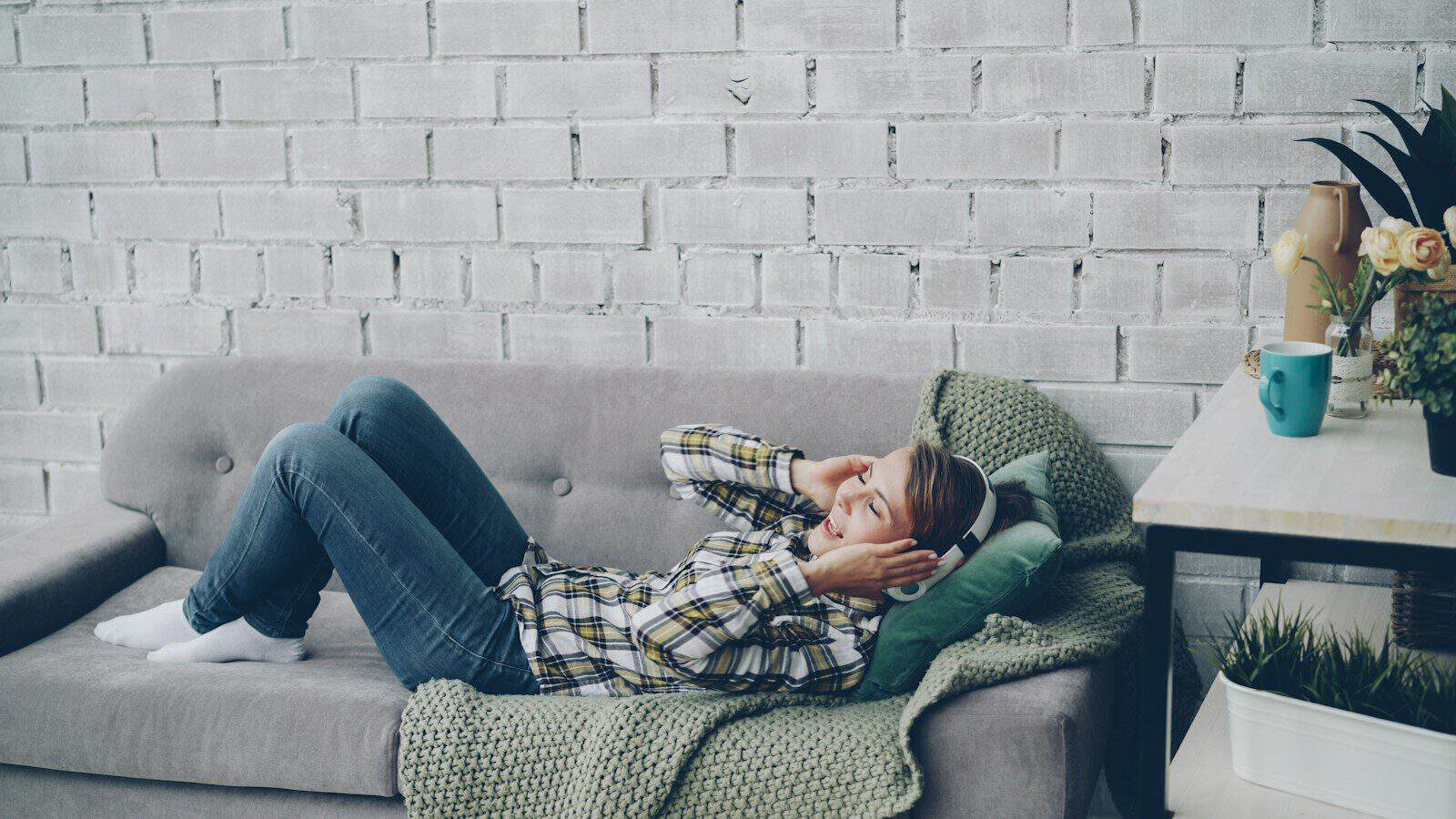 Woman relaxing on a sofa with hands behind head