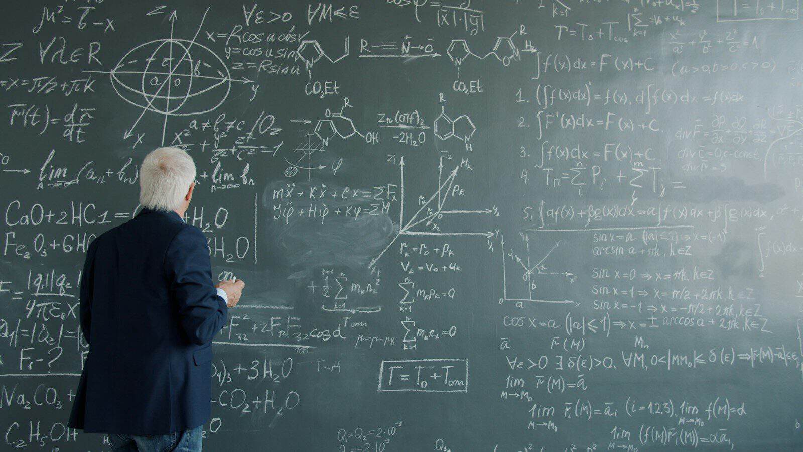 Professor writing complex formulas on a chalkboard