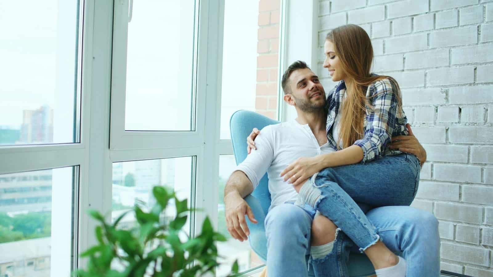 Couple sitting together in a chair by window