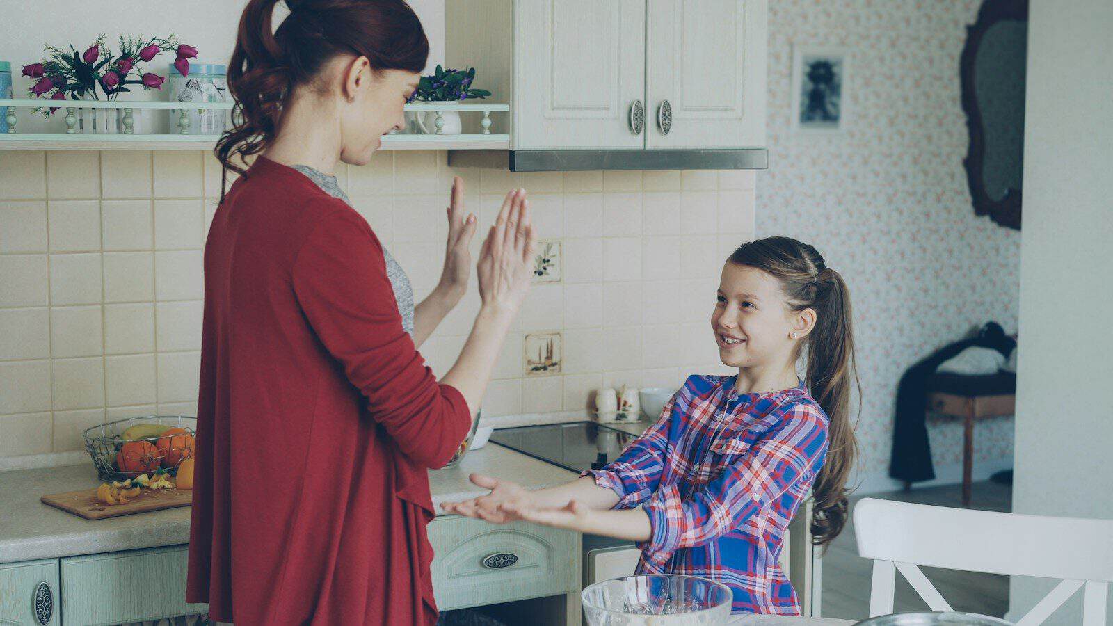 A mother and daughter are playing in the kitchen