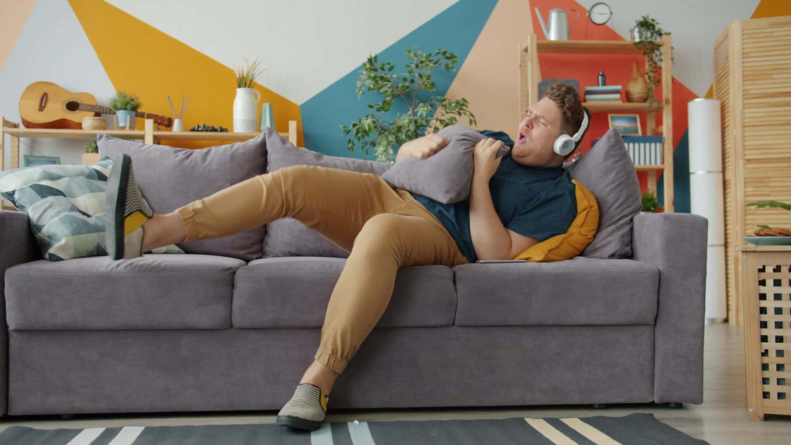 Man listening to music on couch with pillow