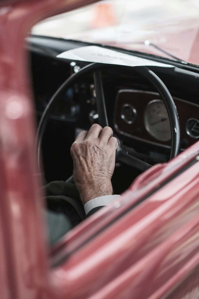 A man driving a car with his hand on the steering wheel