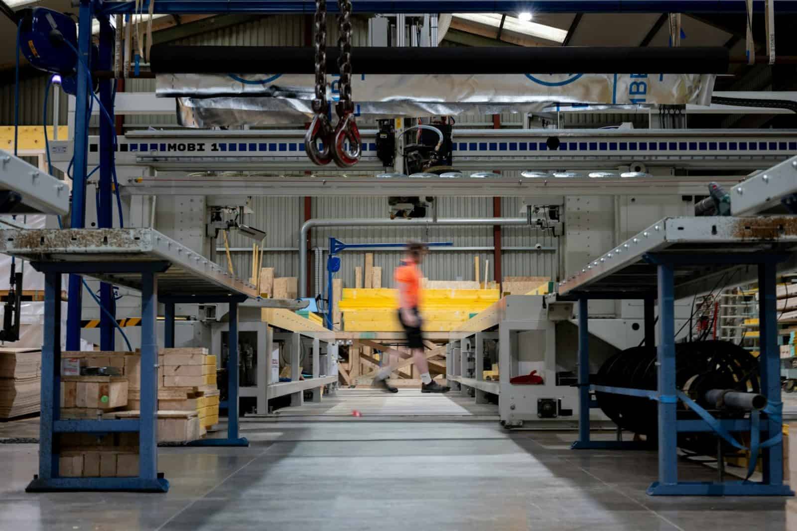 A person in an orange shirt walking through a factory with industrial machinery