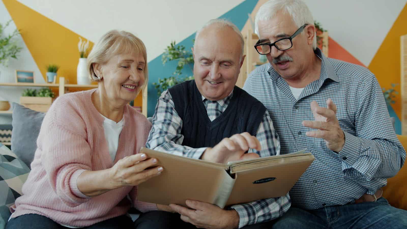 Three seniors looking at a photo album together