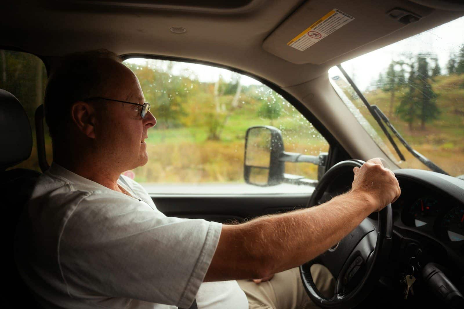 A man driving a car on a rural road