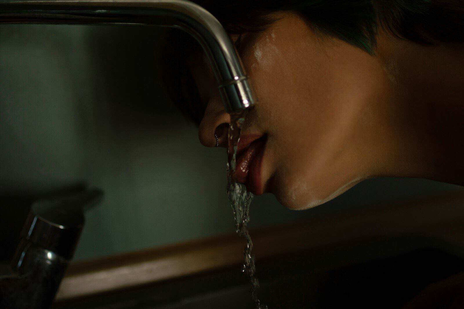 A person drinking water from a faucet