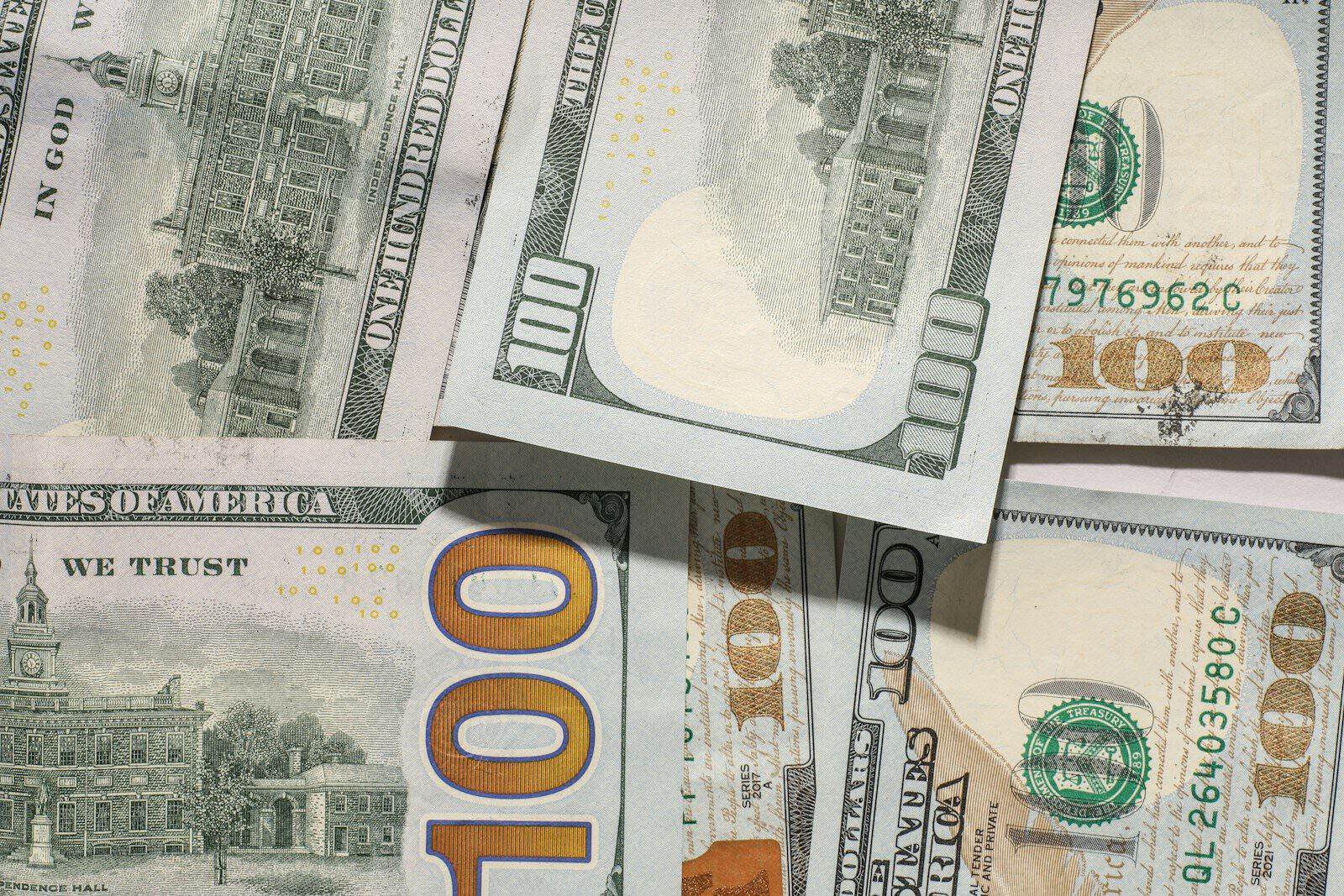 One hundred dollar bills scattered on a surface