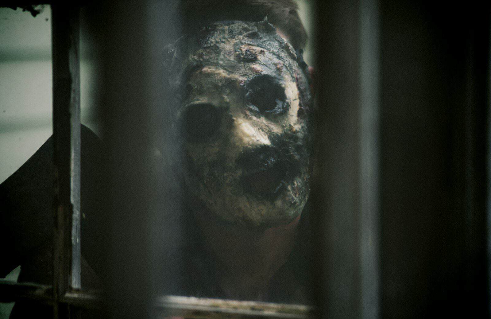A creepy looking person looking through a window